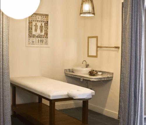 a bathroom with a sink and a bench next to a mirror at Hotel Pousada Laje de Itauna in Saquarema
