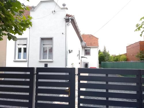 a white house with a black fence at Jade Vendégház in Pápa