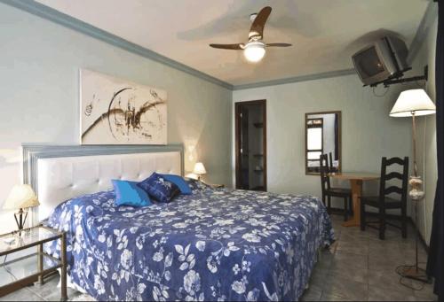 a bedroom with a bed with a blue comforter at Hotel Pousada Laje de Itauna in Saquarema