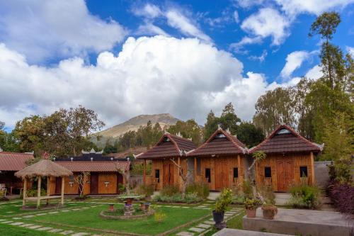 a group of houses with a mountain in the background at Batur Bamboo Cabin by ecommerceloka in Kintamani