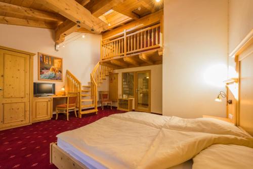 a bedroom with a bed and a desk and a staircase at Gasthof Ochsalm in Kirchberg in Tirol
