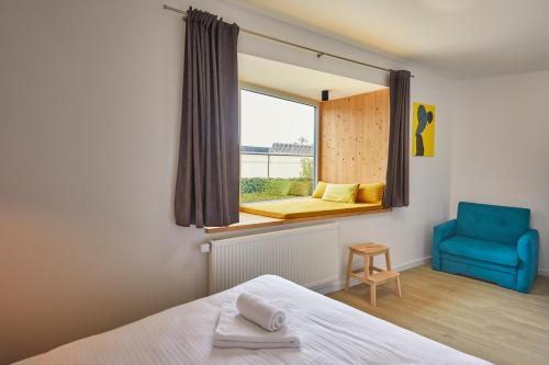 een slaapkamer met een bed en een raam met een blauwe stoel bij Apartmány LAMA in Nižné Malatíny