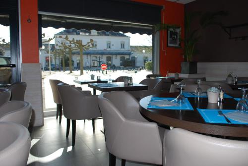 a restaurant with tables and chairs with a view of a street at Cit'Hotel Le Chêne Vert in Les Sables-d'Olonne