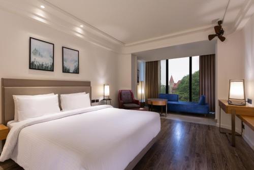 a bedroom with a large white bed and a desk at The Oasis Mussoorie - A Member of Radisson Individuals in Mussoorie