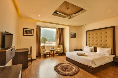 a bedroom with a large bed and a television at Hotel Vasundhara Palace in Rishīkesh