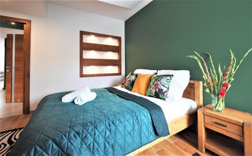 a bedroom with a bed and a green wall at VIP Apartamenty Stara Polana in Zakopane