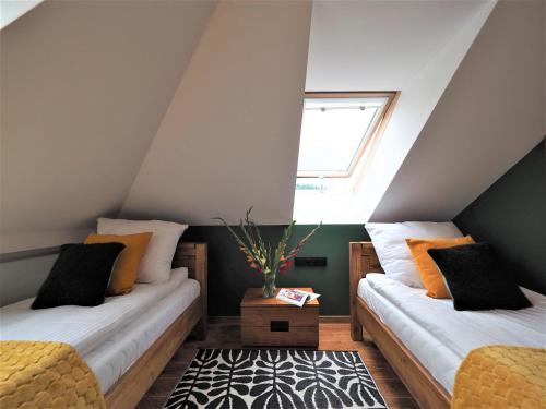 a attic bedroom with two beds and a window at VIP Apartamenty Stara Polana in Zakopane