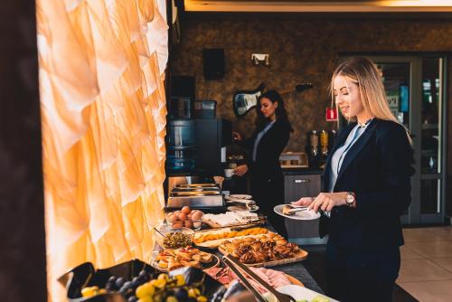
a woman standing in front of a buffet table filled with food at Plaza Hotel Plovdiv in Plovdiv
