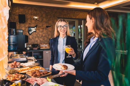 two women holding a plate of food and a glass of wine at Plaza Hotel Plovdiv - Free Parking in Plovdiv