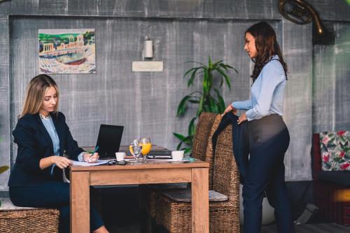 two women sitting at a table with a laptop at Plaza Hotel Plovdiv - Free Parking in Plovdiv
