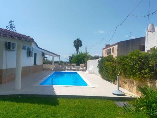 a swimming pool in a yard next to a house at Villa delle Muse in Fontane Bianche