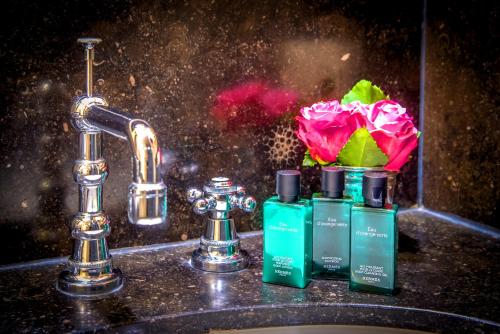a sink with two bottles of soap and a flower at Canalside House - Luxury Guesthouse in Bruges
