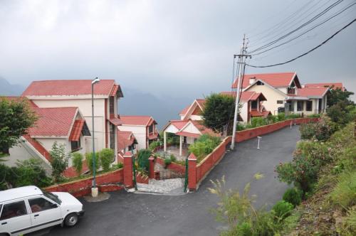 a white car parked in front of a row of houses at Manla Homes Resort in Mashobra