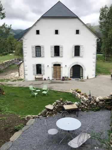 a white barn with tables and chairs in front of it at L 'Air d'Aspe in Accous