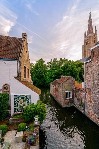 a view of a river with buildings and a church at Canalside House - Luxury Guesthouse in Bruges