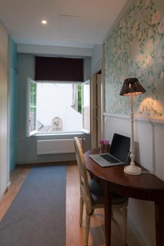 a dining room with a table with a laptop on it at Canalside House - Luxury Guesthouse in Bruges