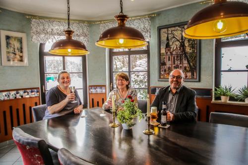 3 Personen sitzen an einem Tisch in einem Restaurant in der Unterkunft Landhotel am Wenzelbach in Prüm