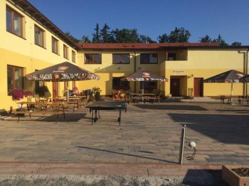 a patio with tables and umbrellas in front of a building at Penzion a restaurace Zlatovláska u zámku Červená Lhota in Jižná