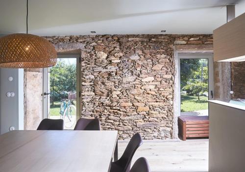 a kitchen with a stone wall and a table and chairs at Casa da Oliveira in Caminha