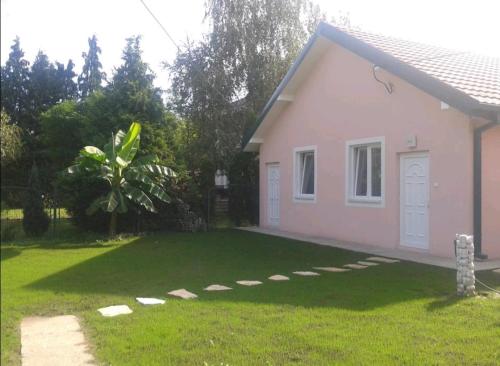a small pink house with a grass yard at Apartman Garden House in Voždovac
