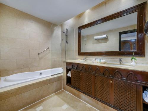 a bathroom with a tub and a sink and a mirror at JAZ Belvedere in Sharm El Sheikh