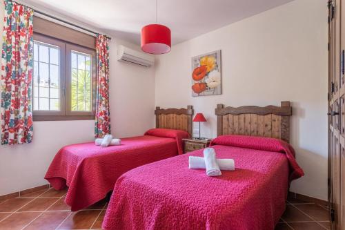 two beds in a room with red sheets at Villa Natalia in Nerja