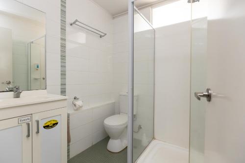 
a white toilet sitting next to a shower in a bathroom at Broome Time Resort in Broome
