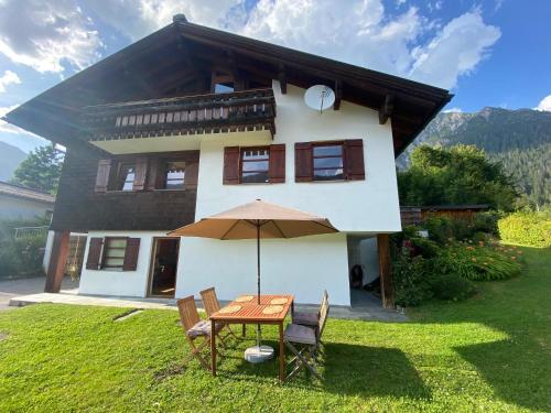 a table with an umbrella in front of a house at Haus Maschol in Wald am Arlberg