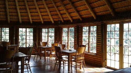 a dining room with tables and chairs and windows at Ledges Retreat in Bergville