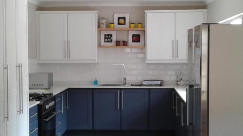 a blue kitchen with white cabinets and a sink at Ledges Retreat in Bergville