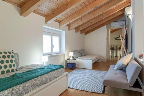 een slaapkamer met een bed en een bank bij Palazzo Tergesteo Tirabora Suite Apartments in Trieste
