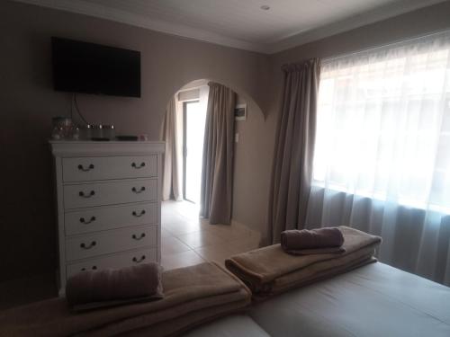 a bedroom with a bed and a dresser and a window at Ledges Retreat in Bergville