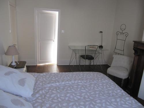 a bedroom with a bed and a table and a chair at Suite Sainte Anne in Beaumont-sur-Sarthe