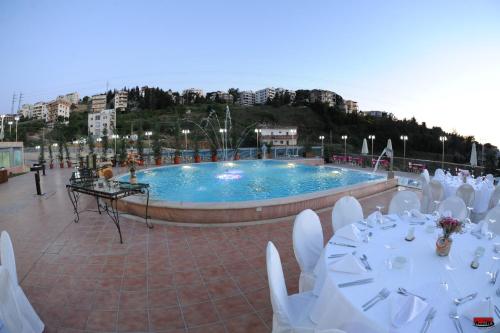 una piscina con mesas blancas y sillas frente a ella en Golden Lili Resort & Spa, en Aley