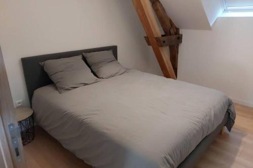- un lit avec des draps et des oreillers blancs dans l'établissement Gîte au cœur des Combrailles, à Saint-Georges-de-Mons