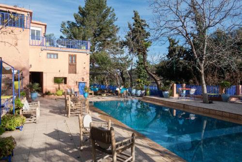 a swimming pool with chairs in front of a house at Auberge le Maquis in Aghbalou