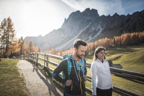 a man and a woman walking on a path in the mountains at Hotel Laurin in Dobbiaco