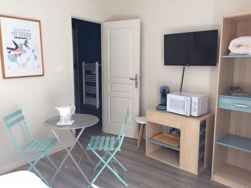 una pequeña sala de estar con mesa y TV. en Chambre dans dépendance Maison de Ville + abri vélos en Saumur
