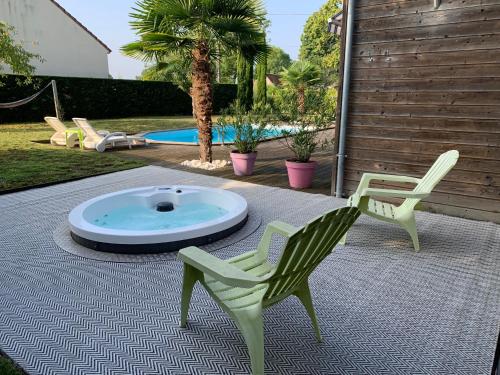 a patio with two lawn chairs and a hot tub at Le Lagon in Jargeau