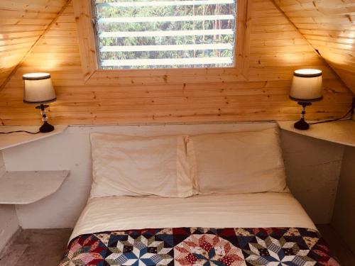 een bed in een kleine kamer met 2 lampen bij #1 cabin Tiny house with kitchen equipped with essentials near at the Volcano Park in Pahoa