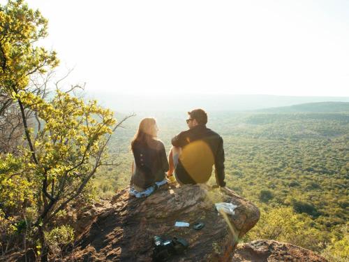 a man and woman sitting on a rock with a guitar at Lindani Game and Lodges in Vaalwater