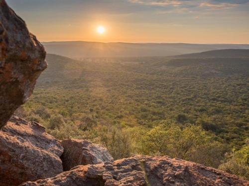 a sunset from the top of a mountain with a view of a valley at Lindani Game and Lodges in Vaalwater