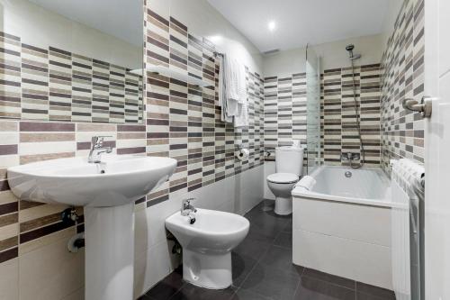 a bathroom with a sink and a toilet and a bath tub at Hostal Los Ángeles in Madrid