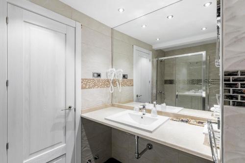 a white bathroom with a sink and a mirror at Hostal Los Ángeles in Madrid