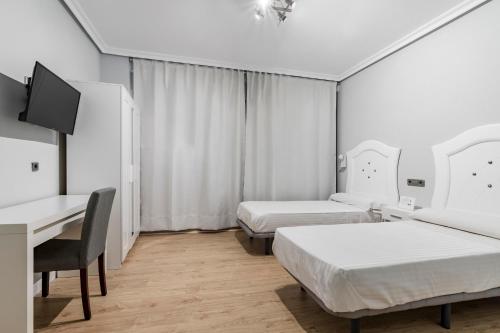 a room with two beds and a desk and a computer at Hostal Los Ángeles in Madrid