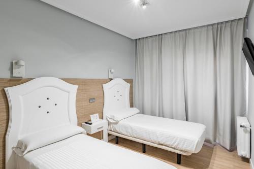 a hotel room with two beds and a window at Hostal Los Ángeles in Madrid