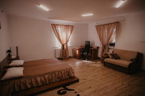 a bedroom with a bed and a couch and a desk at Лісова Пісня Апартаменти in Husyatyn