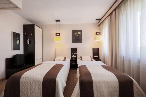 a hotel room with three beds in a room at Hotel Borowiecki in Łódź