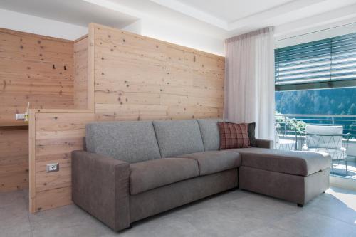 a couch in a living room with a wooden wall at Bellavista - Lake in Molveno