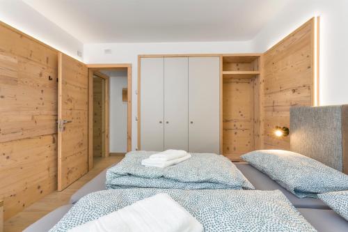 two beds in a room with wooden walls at Bellavista - Lake in Molveno